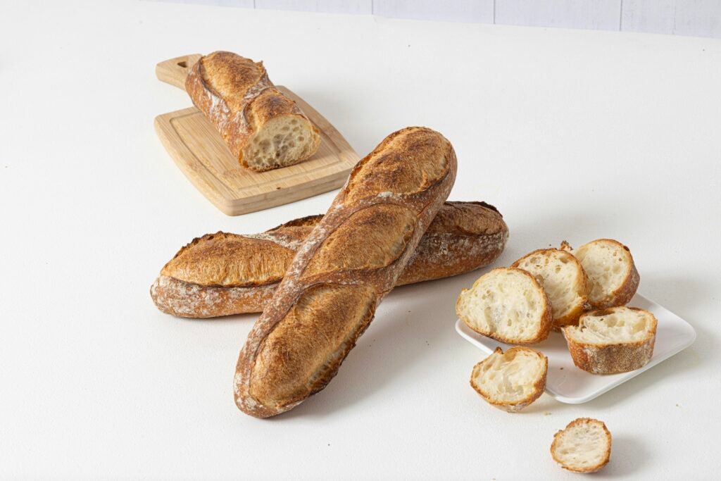 Frisch gebackene Baguettes und mehrere Brotscheiben auf einer weißen Oberfläche, fotografiert aus der Vogelperspektive