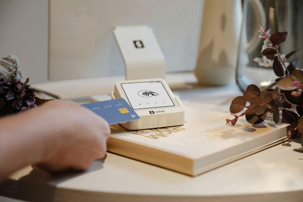 Eine Hand hält eine Kreditkarte und nutzt sie für eine digitale Zahlung an einem Lesegerät.