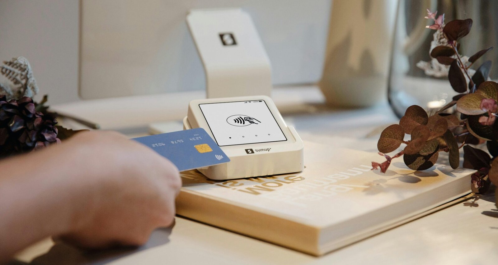 Eine Hand hält eine Kreditkarte und nutzt sie für eine digitale Zahlung an einem Lesegerät.