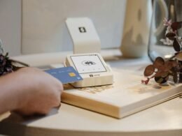 Eine Hand hält eine Kreditkarte und nutzt sie für eine digitale Zahlung an einem Lesegerät.