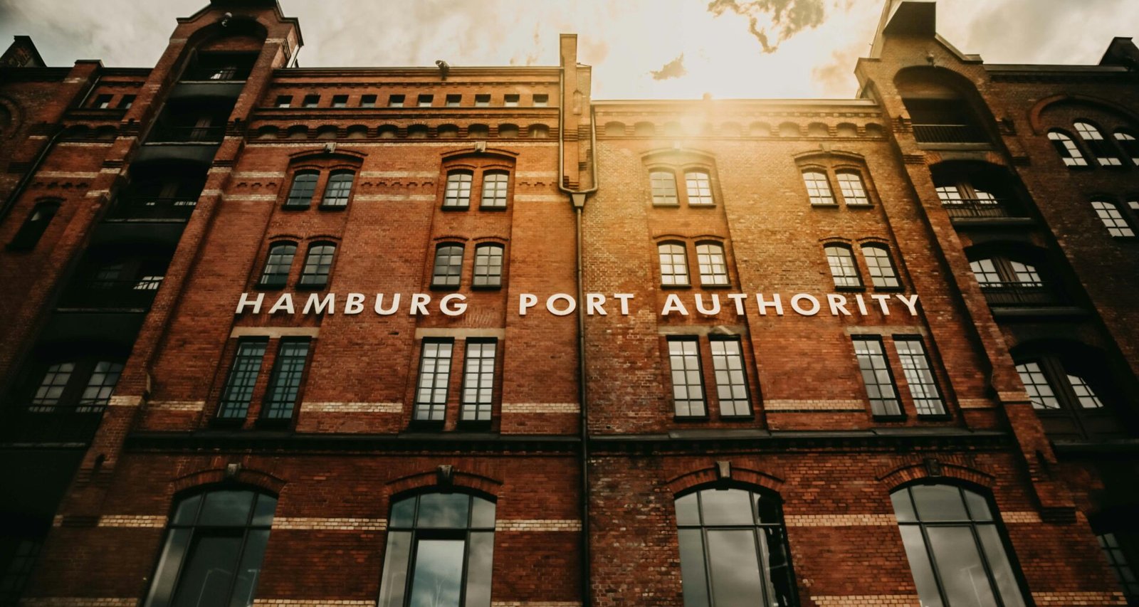 Moderne Gebäudefront der Hamburg Port Authority mit Glasfassade, gelegen im Hamburger Hafenviertel bei Tageslicht.