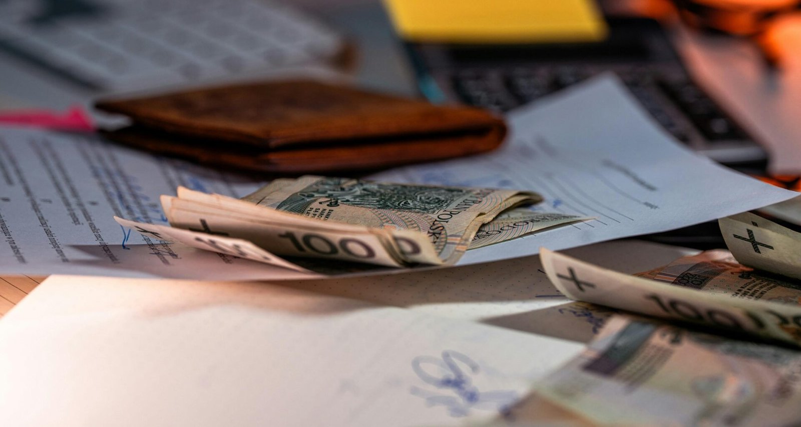 Mehrere Geldscheine und wichtige Unterlagen liegen ordentlich auf einem Schreibtisch im Büro, bereit zur Bearbeitung.