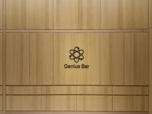 Genius Bar Logo auf einer hellen Holzpaneelwand – modernes Branding in technisch gestalteter Umgebung
