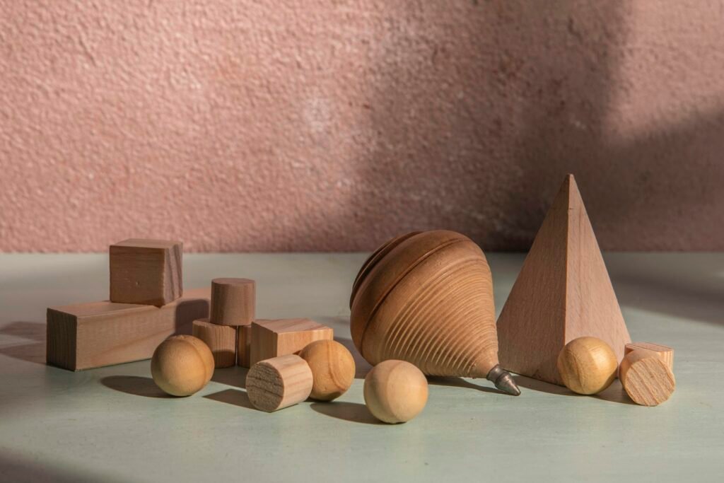 Mehrere hölzerne geometrische Figuren liegen sortiert auf einer ebenen Oberfläche und veranschaulichen verschiedene Formen.