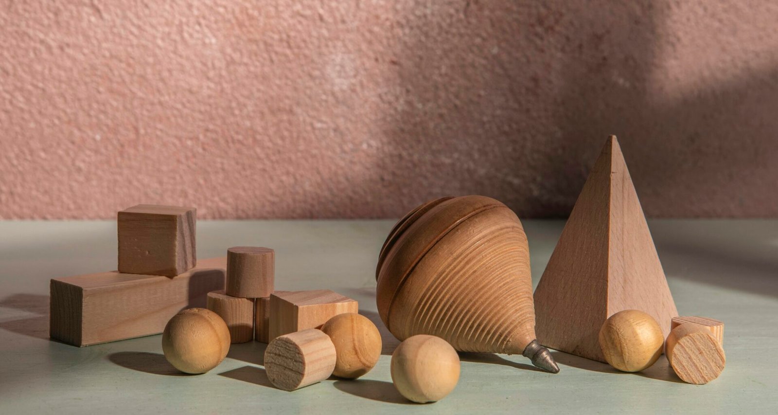 Mehrere hölzerne geometrische Figuren liegen sortiert auf einer ebenen Oberfläche und veranschaulichen verschiedene Formen.