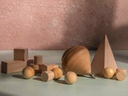 Mehrere hölzerne geometrische Figuren liegen sortiert auf einer ebenen Oberfläche und veranschaulichen verschiedene Formen.