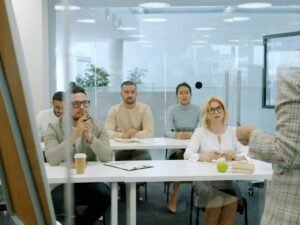 Mehrere Geschäftsleute sitzen in einem modernen Büro und nehmen aufmerksam an einer Präsentation mit Bildschirmen teil.