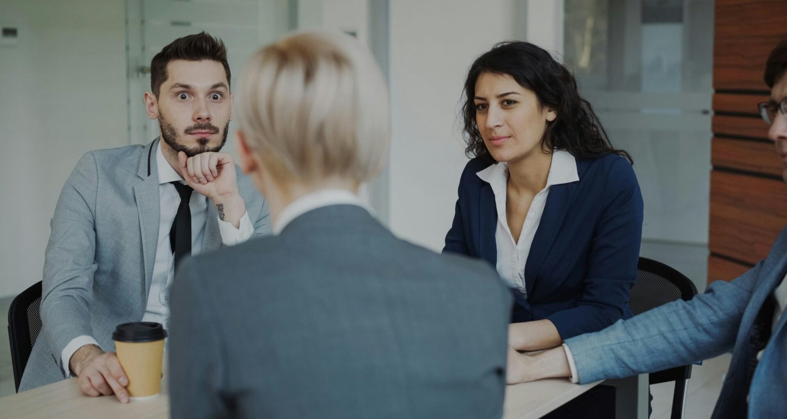 Mehrere Geschäftsleute sitzen um einen Besprechungstisch und führen ein Meeting in einem modernen Büro durch.