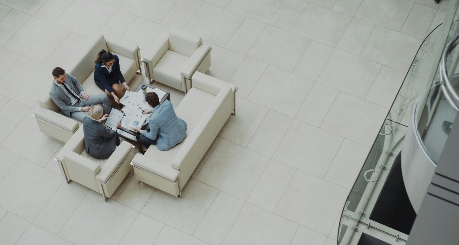 Mehrere Personen sitzen bei einem Geschäftstreffen auf Sofas um einen Tisch und besprechen gemeinsam Projekte.