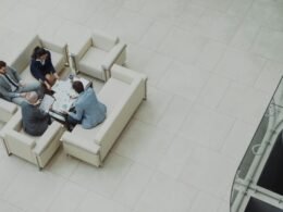 Mehrere Personen sitzen bei einem Geschäftstreffen auf Sofas um einen Tisch und besprechen gemeinsam Projekte.