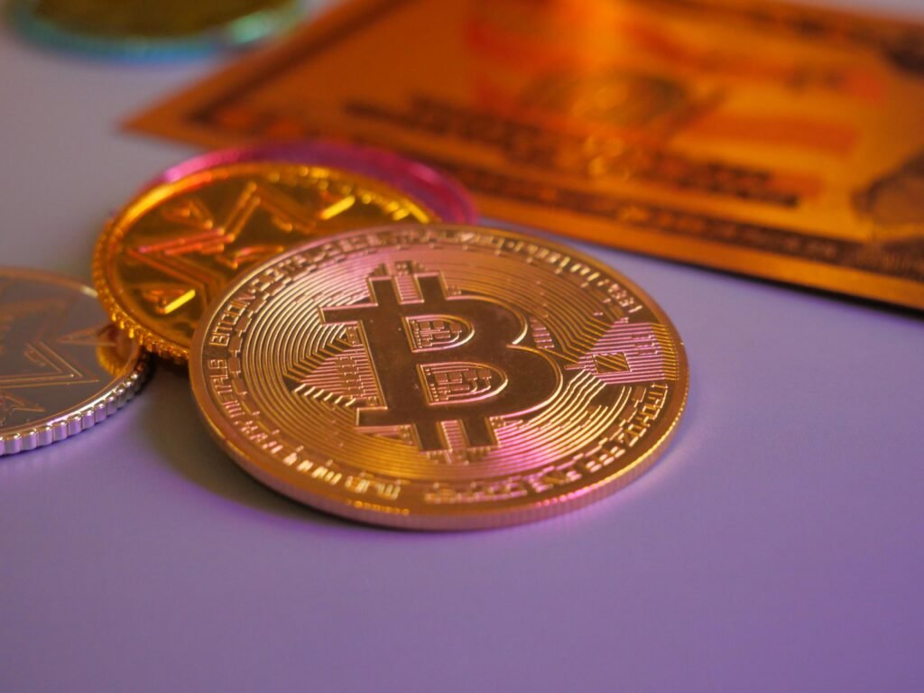 Goldene Bitcoin-Münze neben weiteren Münzen und einer Kreditkarte, Symbol für Kryptowährungen und digitales Bezahlen