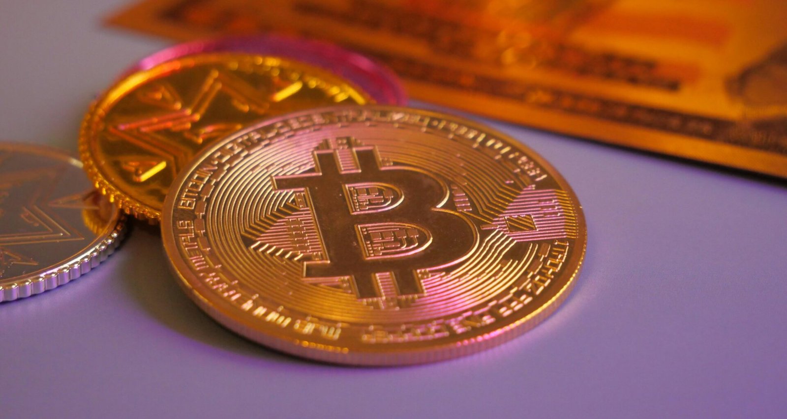 Goldene Bitcoin-Münze neben weiteren Münzen und einer Kreditkarte, Symbol für Kryptowährungen und digitales Bezahlen