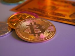 Goldene Bitcoin-Münze neben weiteren Münzen und einer Kreditkarte, Symbol für Kryptowährungen und digitales Bezahlen