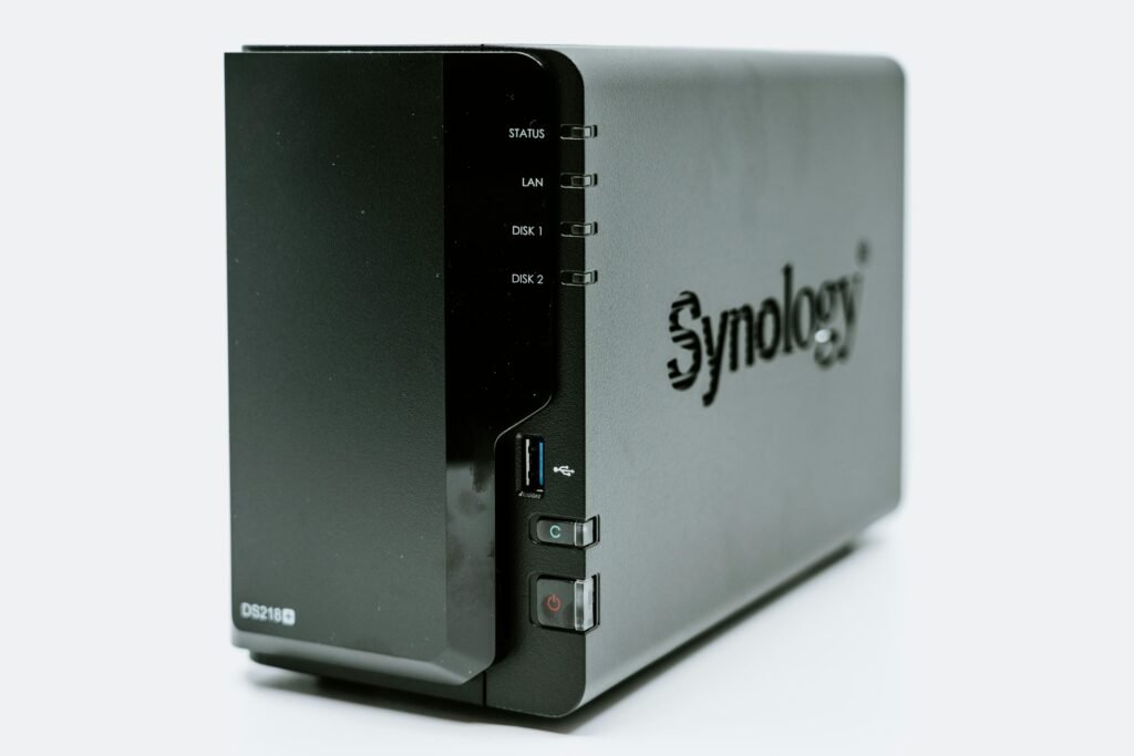 Ein graues Synology NAS-Gerät mit mehreren Einschüben, fotografiert aus der Nähe, zur Darstellung moderner Speicherlösungen.