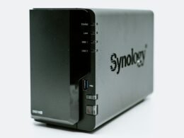 Ein graues Synology NAS-Gerät mit mehreren Einschüben, fotografiert aus der Nähe, zur Darstellung moderner Speicherlösungen.