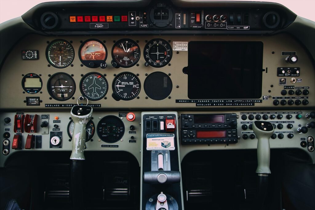 Detailaufnahme von grauen und schwarzen Bedienelementen eines modernen Flugzeug-Cockpits mit verschiedenen Schaltern und Anzeigen.