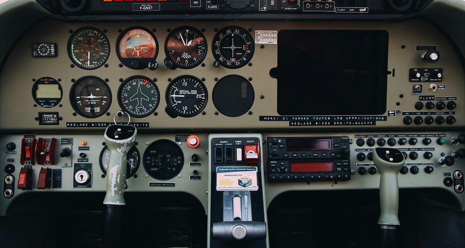 Detailaufnahme von grauen und schwarzen Bedienelementen eines modernen Flugzeug-Cockpits mit verschiedenen Schaltern und Anzeigen.