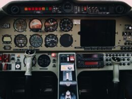 Detailaufnahme von grauen und schwarzen Bedienelementen eines modernen Flugzeug-Cockpits mit verschiedenen Schaltern und Anzeigen.