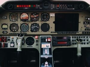 Detailaufnahme von grauen und schwarzen Bedienelementen eines modernen Flugzeug-Cockpits mit verschiedenen Schaltern und Anzeigen.