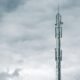 Grauer Radio- oder Funkturm steht bei Tageslicht unter einer dichten Wolkendecke am Himmel