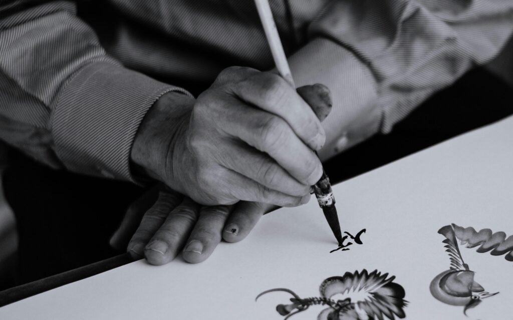 Schwarzweißaufnahme einer Person, die einen Tintenstift in der rechten Hand hält, Fokus auf das Schreibwerkzeug