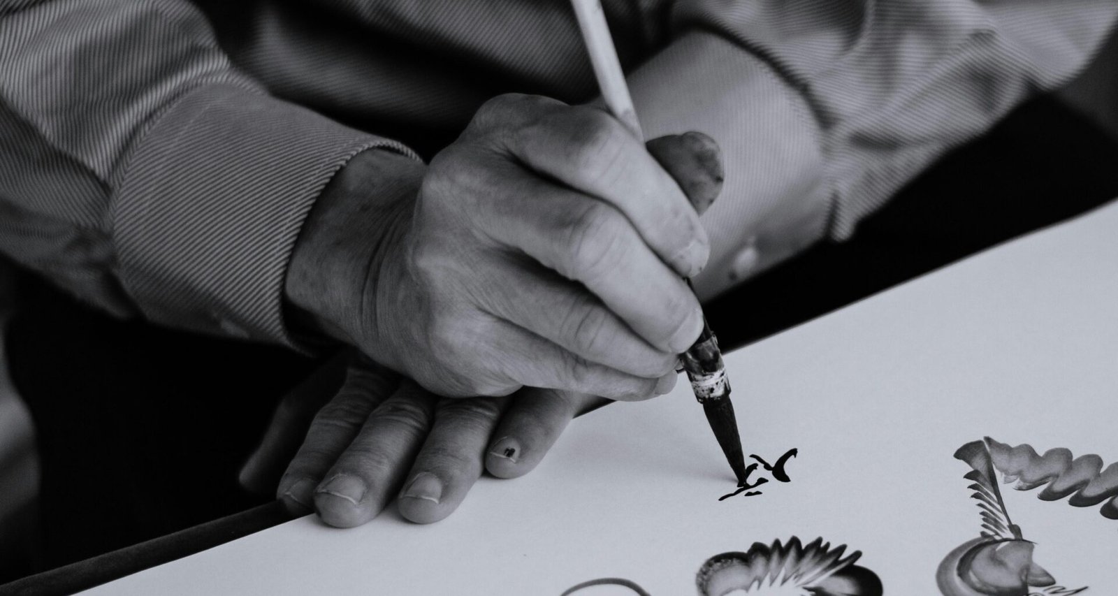 Schwarzweißaufnahme einer Person, die einen Tintenstift in der rechten Hand hält, Fokus auf das Schreibwerkzeug