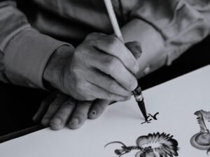 Schwarzweißaufnahme einer Person, die einen Tintenstift in der rechten Hand hält, Fokus auf das Schreibwerkzeug