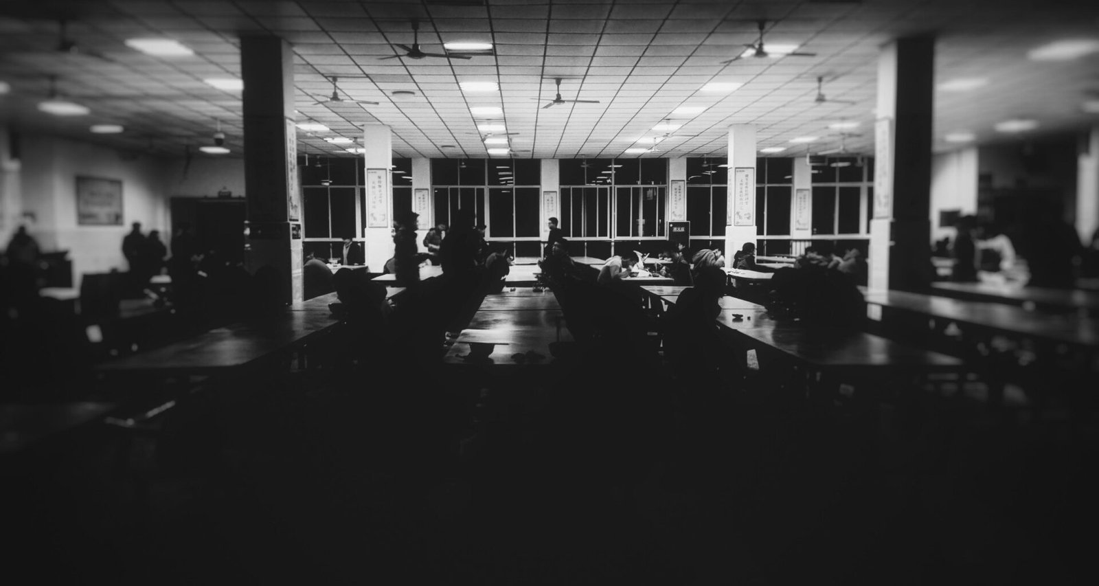 Grayscale-Foto eines modernen Raumes mit mehreren Tischen, geeignet für Meetings oder Gruppenarbeit