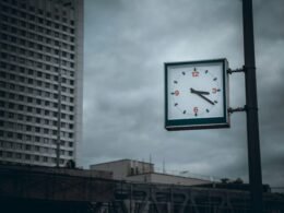 Grüne und weiße analoge Wanduhr auf heller Fläche mit Zeigern auf 10:00 Uhr, Nahaufnahme.
