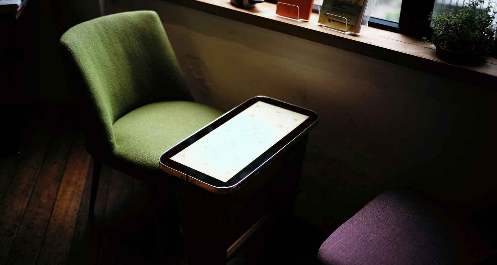 Grüner Stuhl an einem Tisch in einem hellen Raum vor einem Fenster, minimalistisches modernes Interieur im Tageslicht