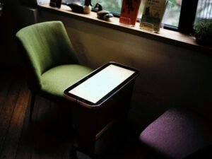 Grüner Stuhl an einem Tisch in einem hellen Raum vor einem Fenster, minimalistisches modernes Interieur im Tageslicht