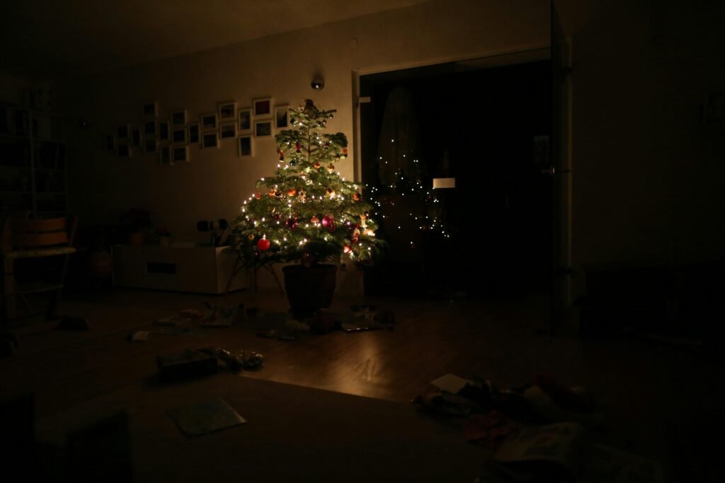 Grüner Weihnachtsbaum mit eingeschalteter Lichterkette steht im Raum, festlich dekoriert, ohne sichtbare Personen