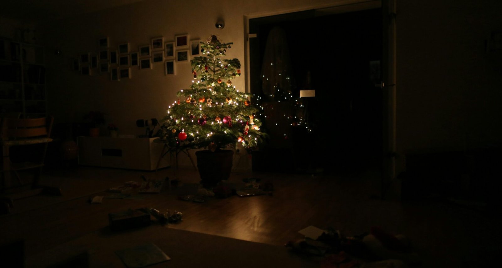 Grüner Weihnachtsbaum mit eingeschalteter Lichterkette steht im Raum, festlich dekoriert, ohne sichtbare Personen