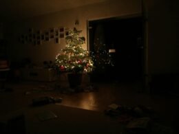 Grüner Weihnachtsbaum mit eingeschalteter Lichterkette steht im Raum, festlich dekoriert, ohne sichtbare Personen