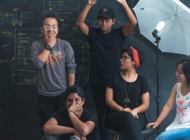 Mehrere Personen arbeiten gemeinsam in einem modernen Studio mit Tischen, Laptops und Notizbüchern