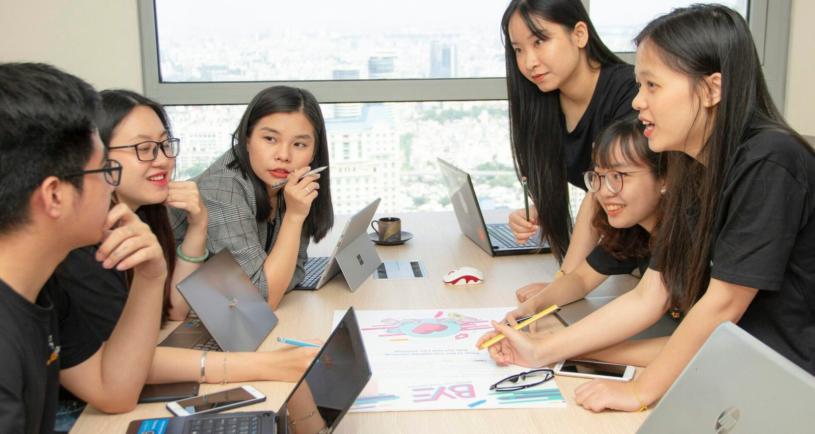 Mehrere Personen sitzen zusammen an einem Tisch und nutzen Laptops für die gemeinsame Arbeit an einem Projekt.
