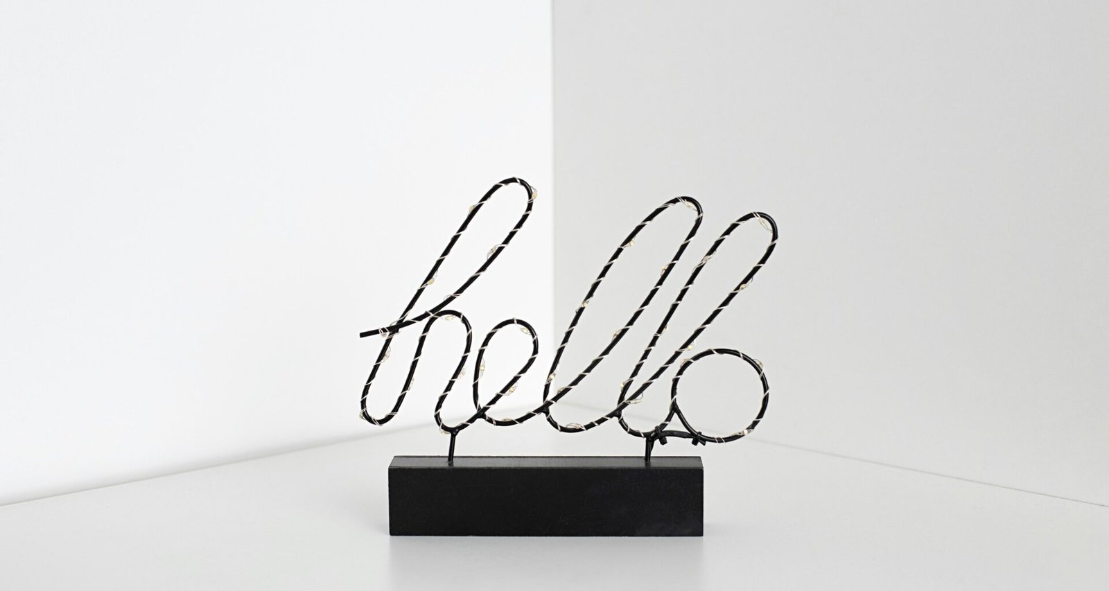Minimalistisches Schild mit der Aufschrift 'Hello' an einer hellen Wand, schlicht gestaltet und zentral platziert.