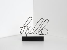 Minimalistisches Schild mit der Aufschrift 'Hello' an einer hellen Wand, schlicht gestaltet und zentral platziert.