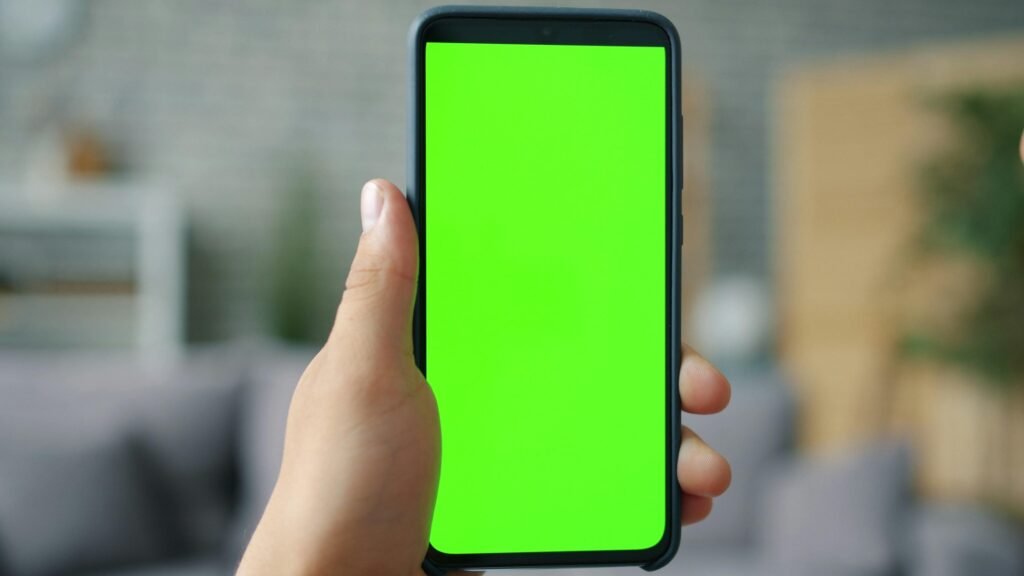 Hand hält ein Smartphone mit grünem Bildschirm, geeignet als Symbolbild für mobile Technologien und digitale Anwendungen.