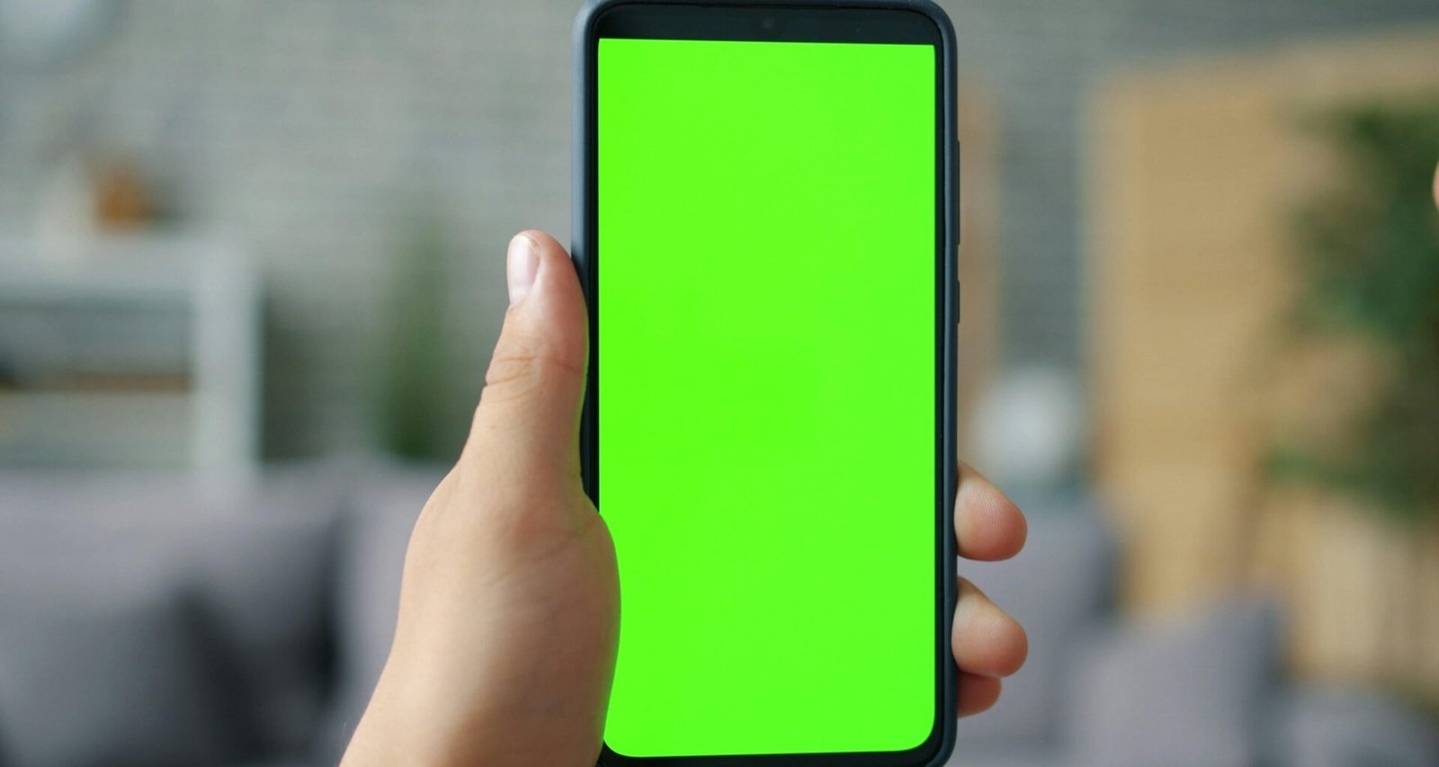Hand hält ein Smartphone mit grünem Bildschirm, geeignet als Symbolbild für mobile Technologien und digitale Anwendungen.