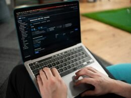 Hände tippen auf der Tastatur eines Laptops, Bildschirm mit geöffnetem Dokument, moderne Arbeitsumgebung