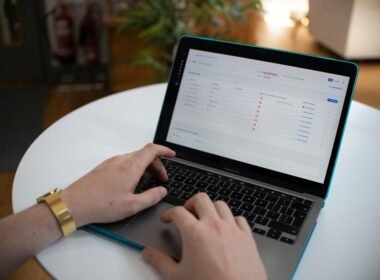 Hände tippen auf einem Laptop, auf dessen Bildschirm eine Tabellenkalkulation geöffnet ist