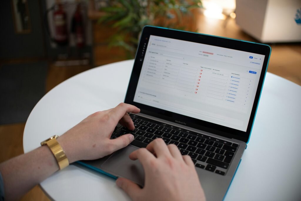 Hände tippen auf einer Laptop-Tastatur, während auf dem Bildschirm eine geöffnete digitale Tabelle angezeigt wird
