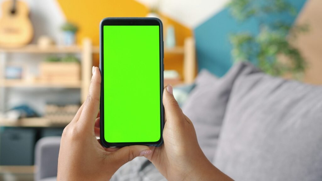 Zwei Hände halten ein Smartphone mit aktiviertem grünen Bildschirm, bereit für digitale Anwendungen oder Präsentationen.