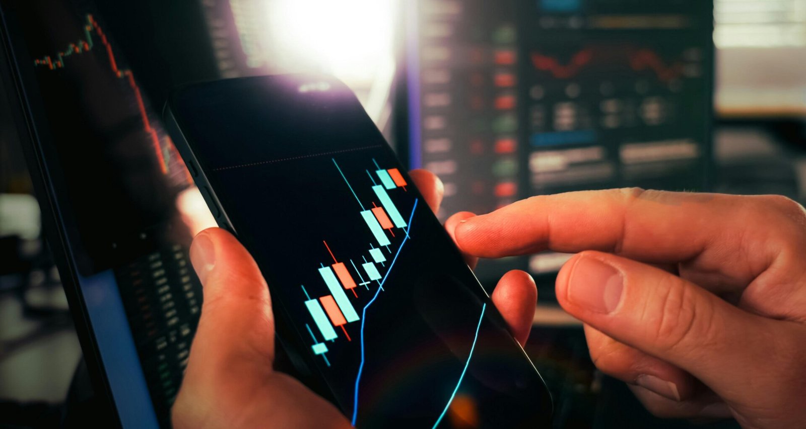 Zwei Hände halten ein Smartphone, auf dessen Bildschirm aktuelle Börsendaten und Finanzdiagramme angezeigt werden.