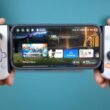 Hände halten ein Smartphone mit einem Gamecontroller-Aufsatz, der das mobile Spielen erleichtert.
