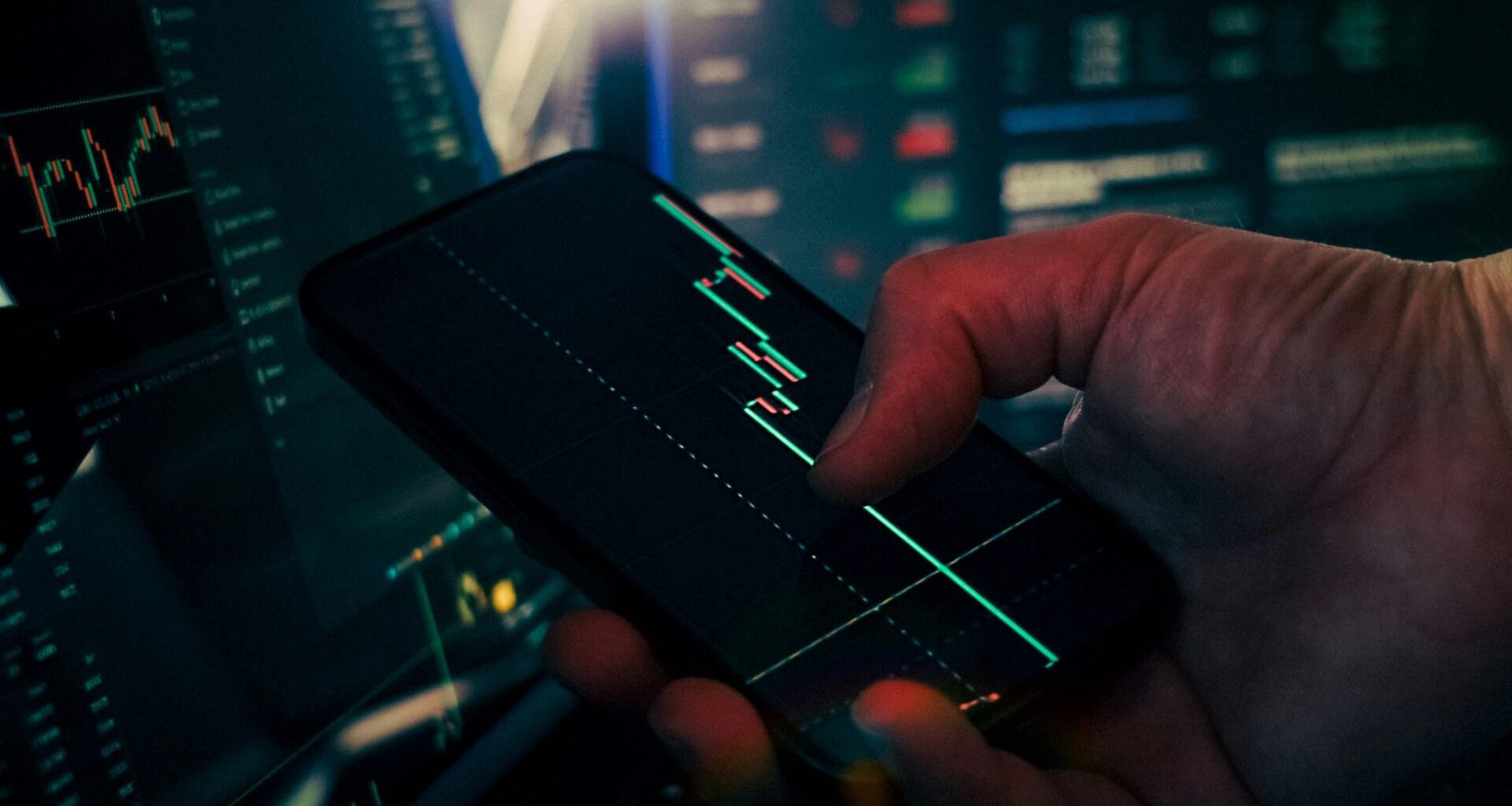 Ein Trader analysiert Börsendaten auf dem Smartphone und nutzt das Handy zur Überwachung von Kursentwicklungen.