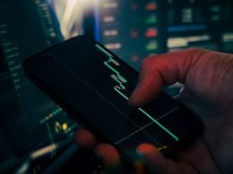 Trader überprüft und analysiert Börsendaten auf seinem Smartphone und nutzt moderne digitale Tools zur Marktbeobachtung.