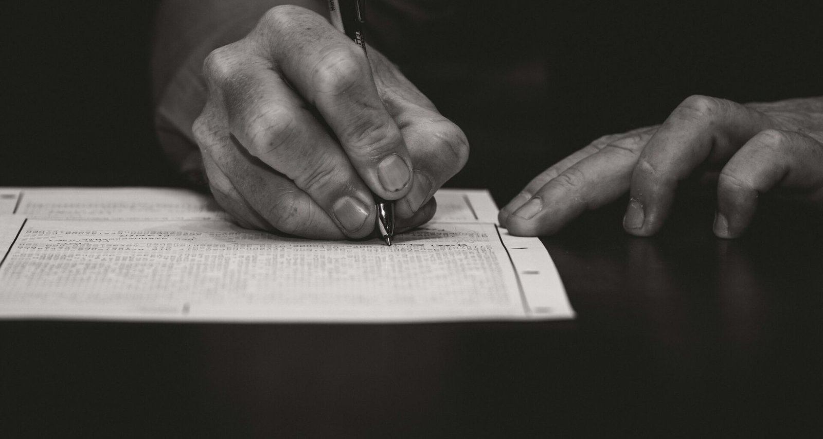 Nahaufnahme einer Hand, die mit einem Füllfederhalter auf weißem Papier schreibt. Fokus auf Stift und Schreibbewegung.