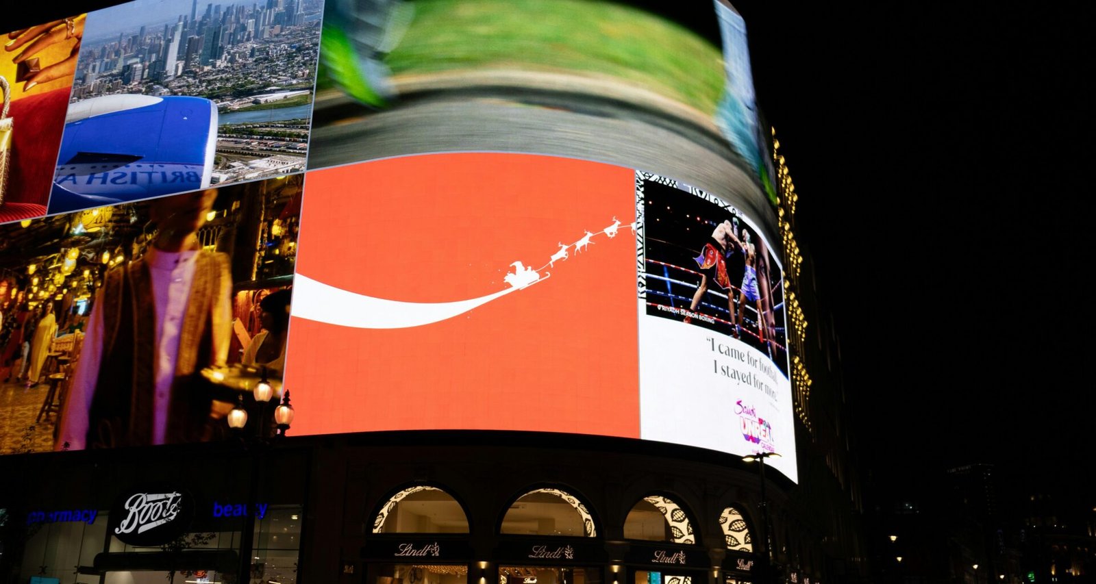 Helle digitale Werbetafeln beleuchten nachts eine geschäftige Stadtstraße mit Passanten und Autos im urbanen Umfeld.